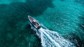 A scorpion rib boat has a wake as it sails through turqouise waters.